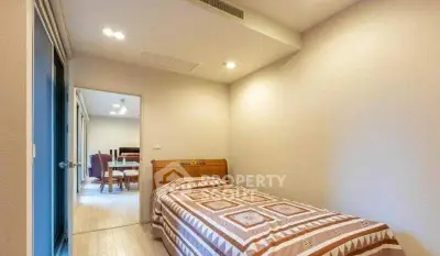 Cozy bedroom with single bed and view into dining area, perfect for urban living.