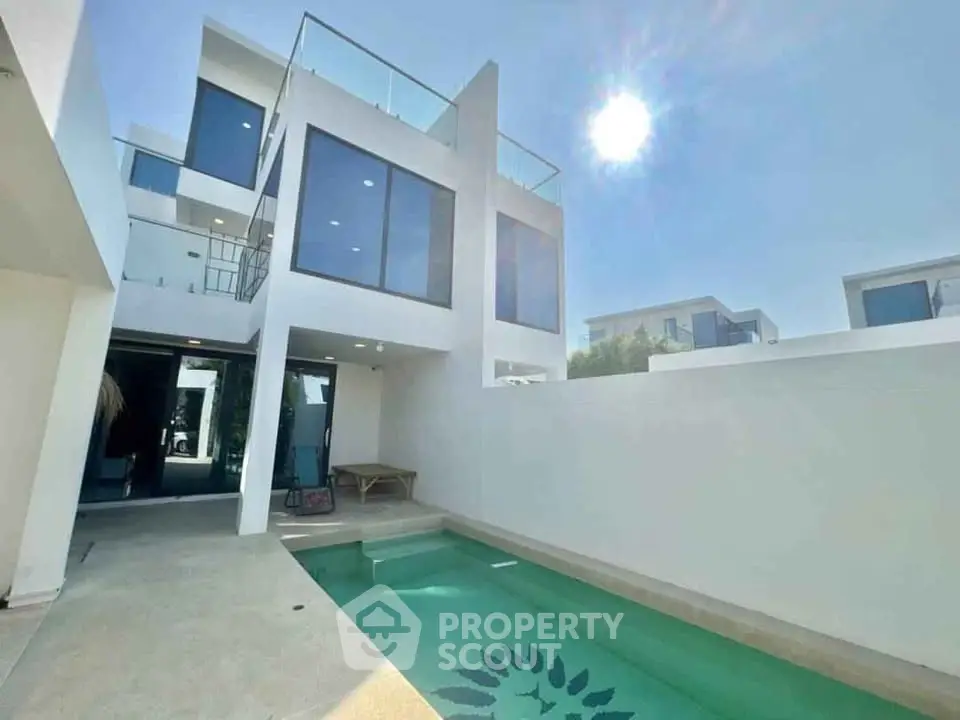 Modern white villa with private pool and sunlit terrace, showcasing contemporary architecture and luxury living.