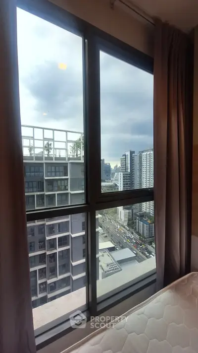 High-rise apartment bedroom with city view through large windows.