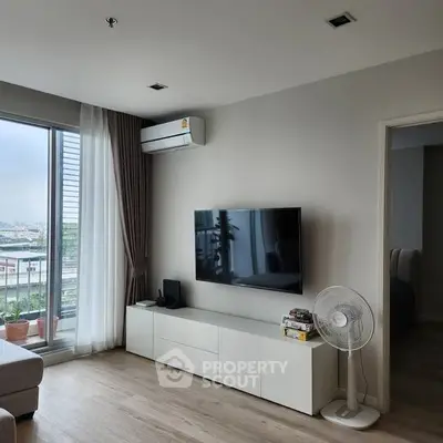 Modern living room with large window and wall-mounted TV, offering a bright and airy atmosphere.