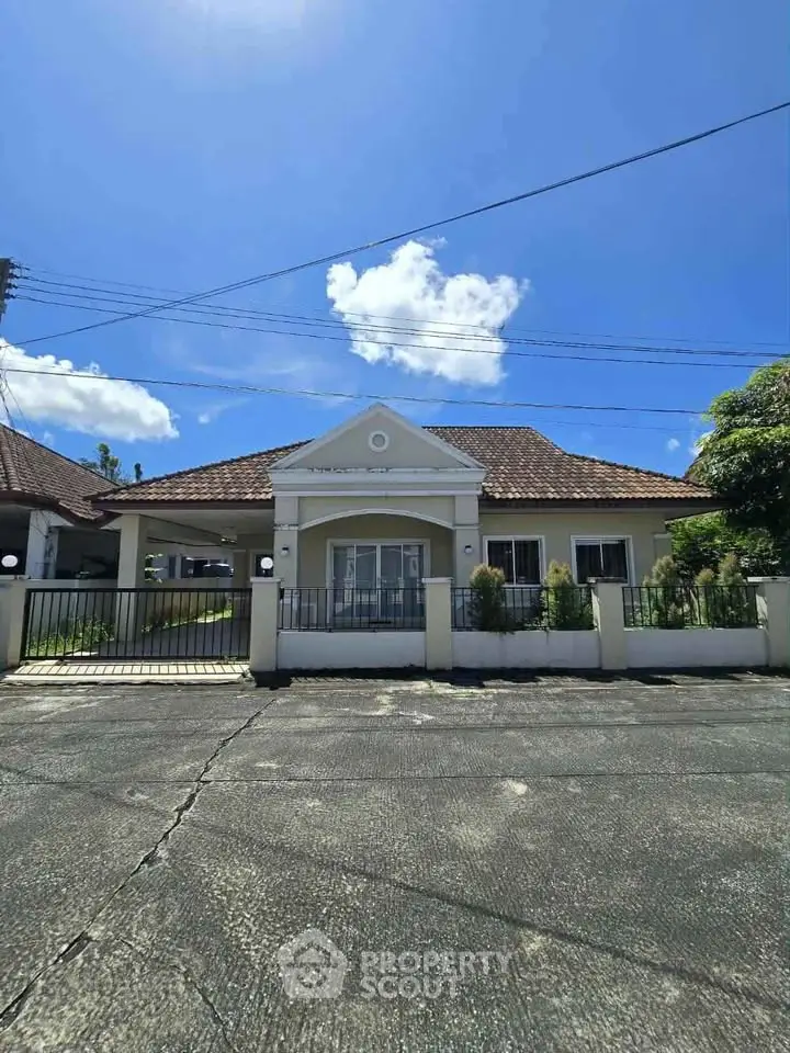 Charming single-story house with tiled roof and spacious driveway under clear blue sky.