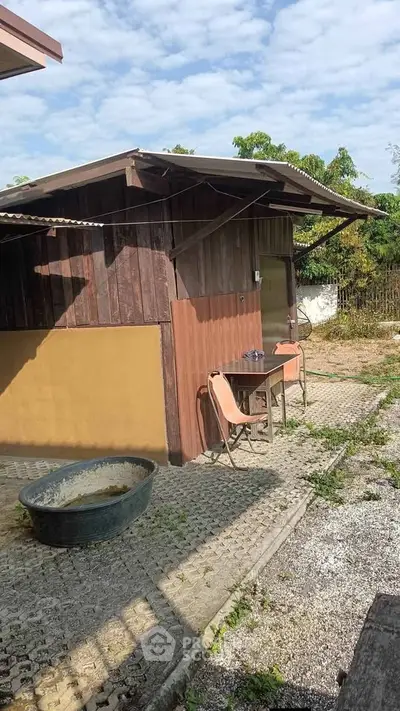 Charming rustic wooden exterior with outdoor seating and lush greenery, perfect for serene living.
