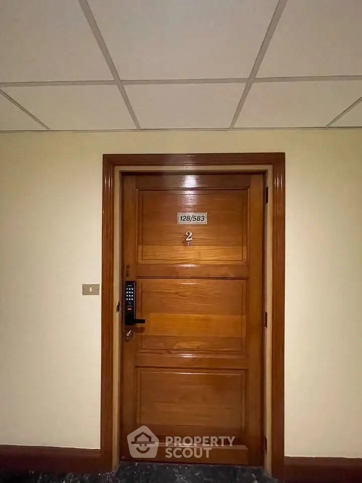 Elegant wooden apartment door with electronic lock in modern building hallway.