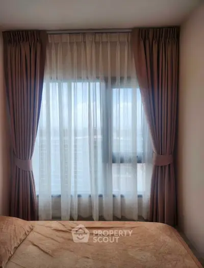 Cozy bedroom with elegant curtains and a city view through the window.