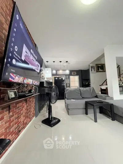 Modern living room with sleek design, featuring a large wall-mounted TV and stylish furniture.
