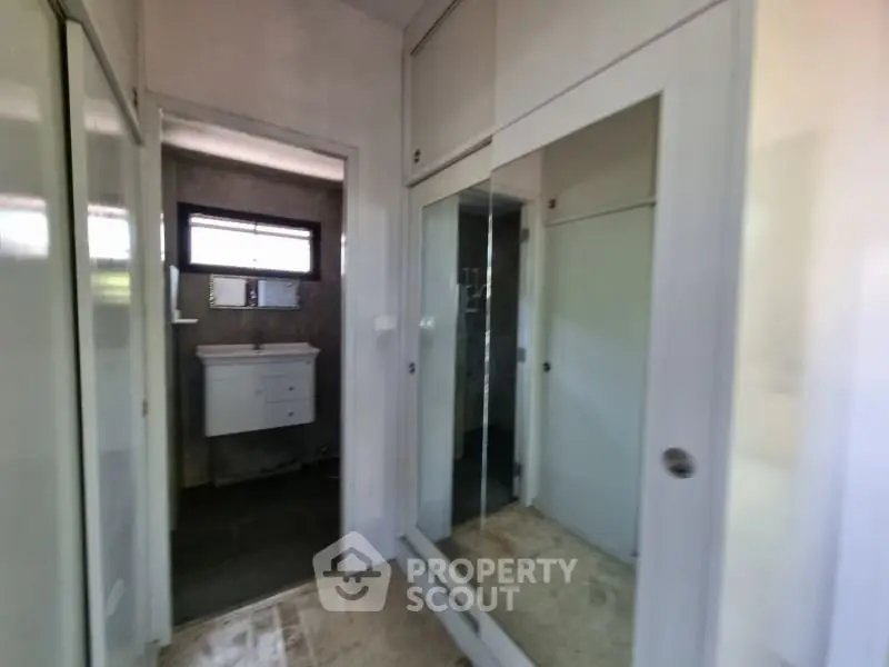 Spacious hallway with mirrored closet leading to modern bathroom