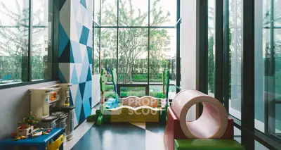 Modern children's playroom with large windows and colorful furniture in luxury apartment building.