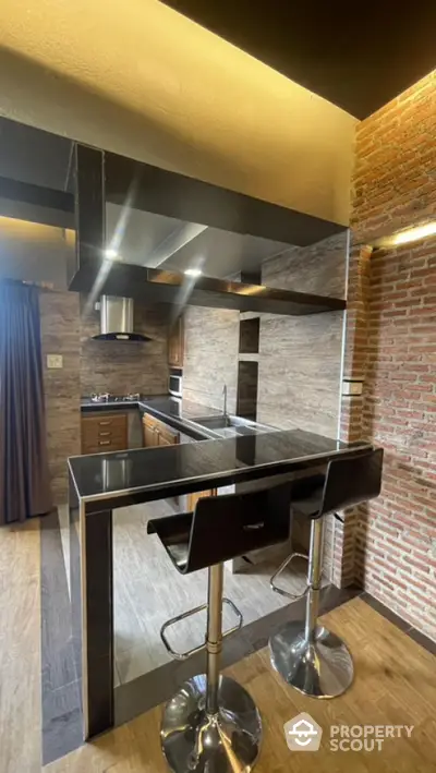 Chic modern kitchen with sleek stainless steel appliances, exposed brick wall, and a stylish breakfast bar with adjustable stools.