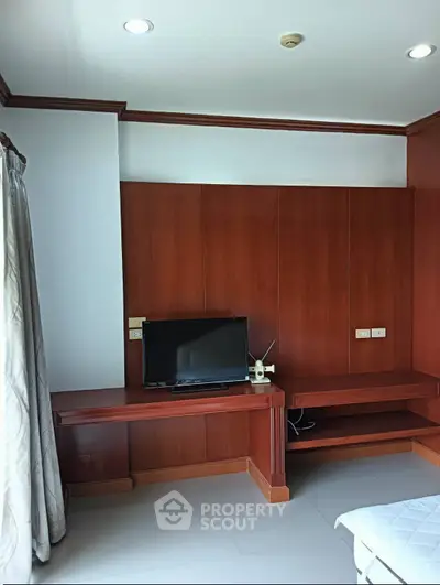 Spacious bedroom with modern wooden paneling and flat-screen TV, perfect for relaxation.