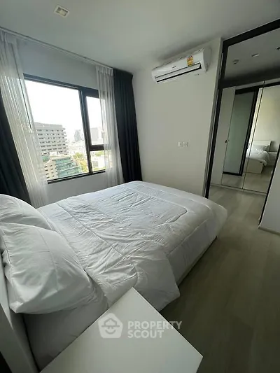 Modern bedroom with city view, featuring a comfortable bed and air conditioning.