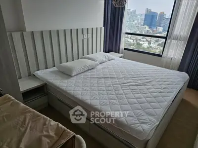 Modern bedroom with city view, featuring a stylish bed and large window for natural light.