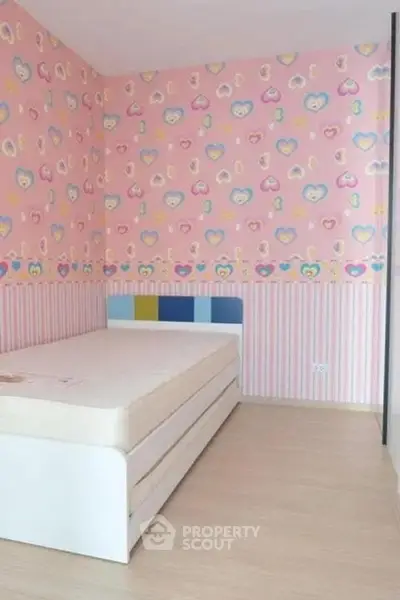 Charming children's bedroom with playful heart-themed wallpaper and cozy bed.