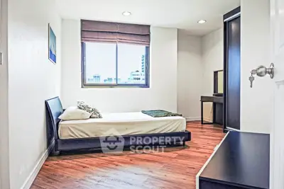 Modern minimalist bedroom with city view and wooden flooring.