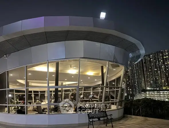 Modern gym with panoramic windows and city skyline view at night.