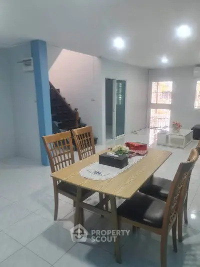 Spacious dining area with modern wooden table and chairs, open layout, and bright natural lighting.
