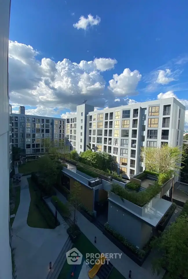 Modern apartment complex with lush gardens and clear blue sky view.