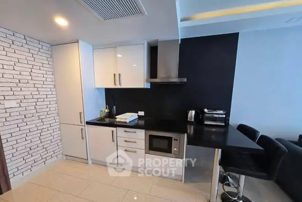 Modern kitchen with sleek black countertops and white cabinetry in stylish apartment.