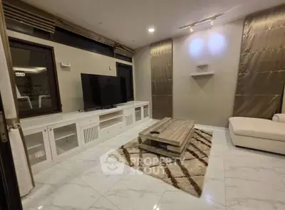 Spacious living room with modern decor, featuring a large TV, elegant furniture, and stylish lighting.