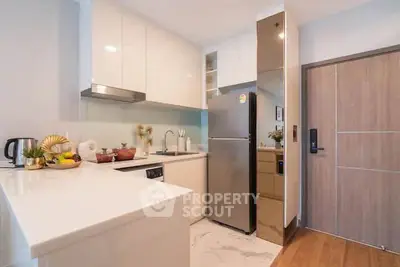 Modern kitchen with sleek white cabinets and stainless steel appliances in a stylish apartment.