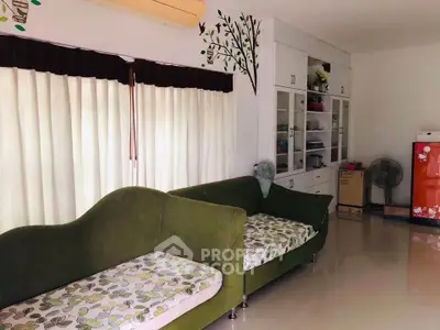 Cozy living room with green sofas and large window, perfect for relaxation.