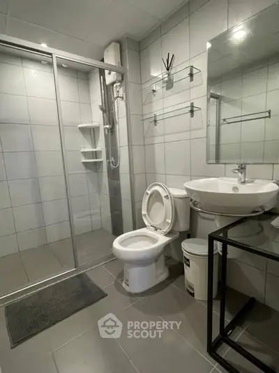 Modern bathroom with glass shower and sleek fixtures in contemporary home.