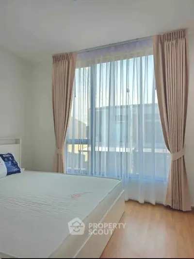 Bright bedroom with large window and elegant curtains, showcasing a serene and inviting atmosphere.