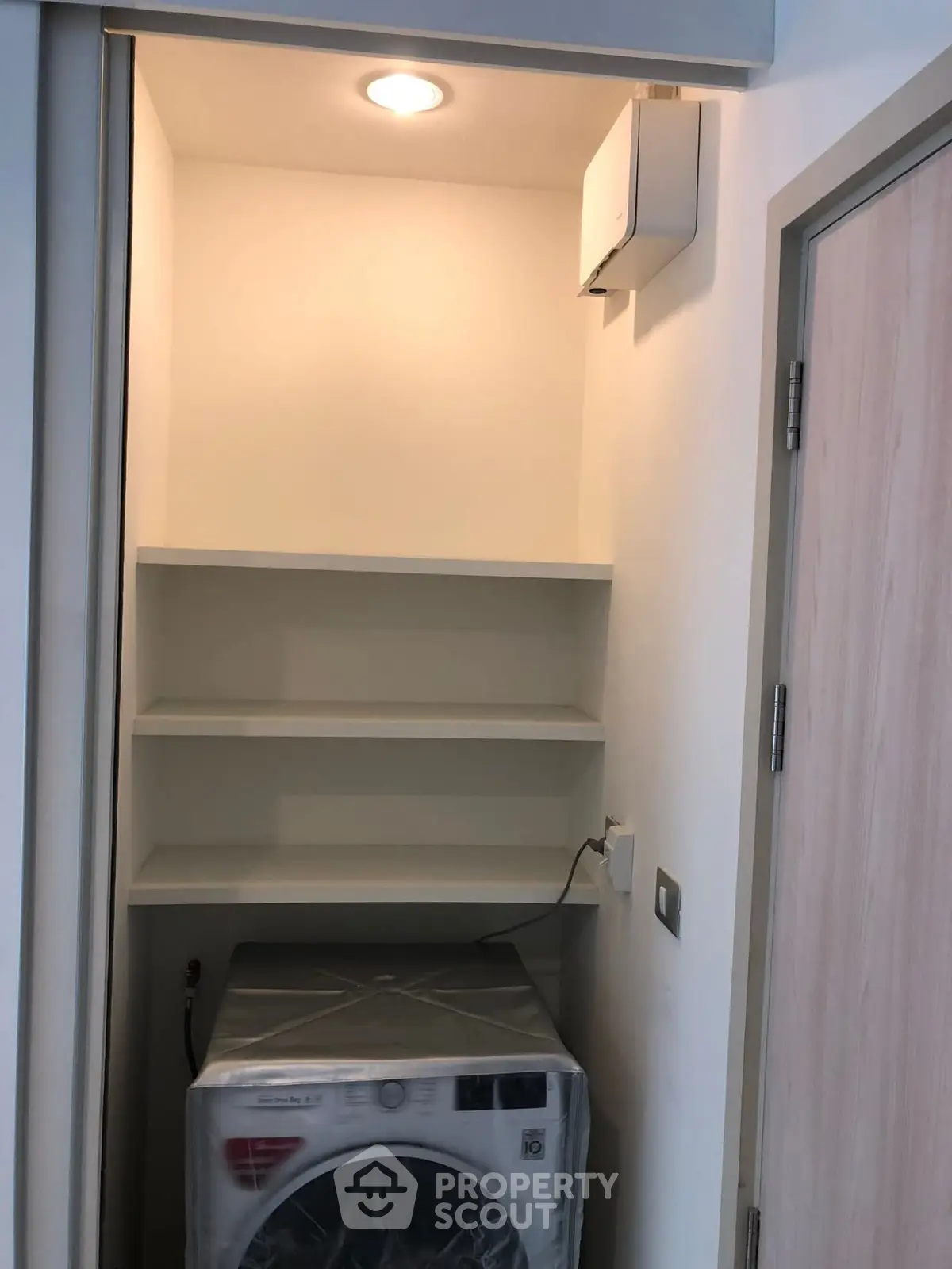 Compact laundry area with modern washing machine and built-in shelves