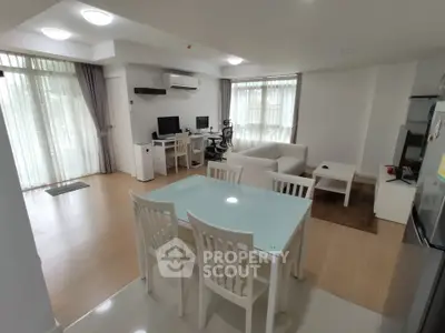 Spacious modern living room with dining area and home office setup, featuring large windows and stylish furniture.