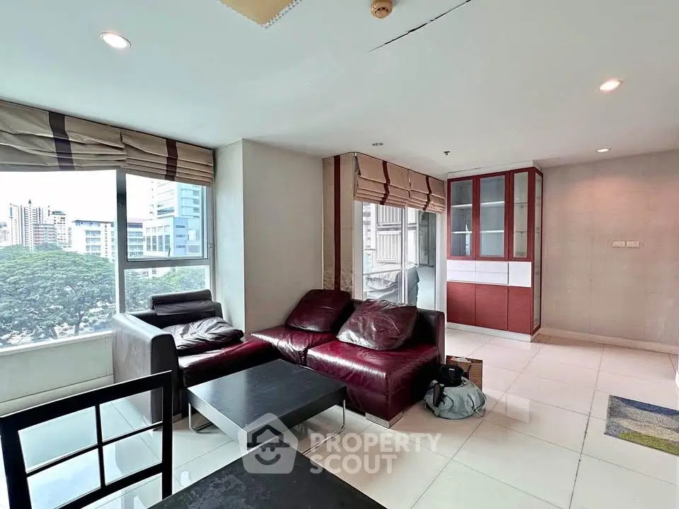 Spacious living room with modern furniture and large windows offering city views.