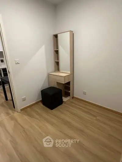 Minimalist bedroom with wooden floors and a sleek vanity set.