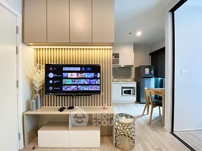 Modern living room with wall-mounted TV and open kitchen layout in stylish apartment.