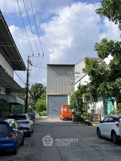 Industrial warehouse exterior with parking area and clear sky view.