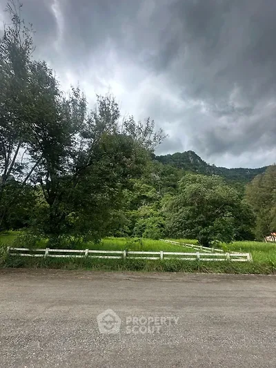 Scenic view of lush greenery and mountains under a cloudy sky, perfect for nature lovers.