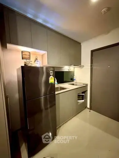 Modern compact kitchen with sleek cabinetry and stainless steel appliances in urban apartment.