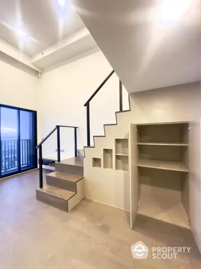 Modern duplex apartment with sleek staircase and built-in storage near balcony.