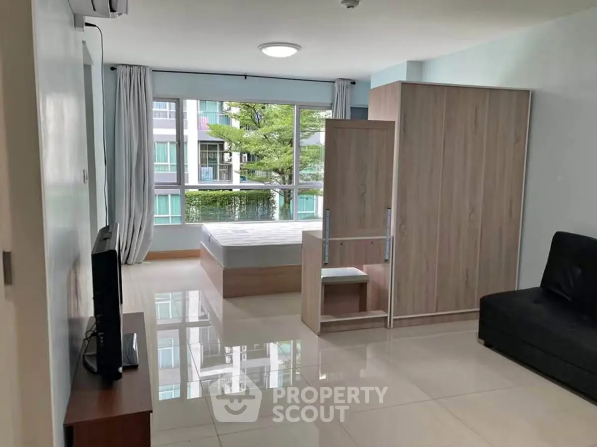 Spacious studio apartment with large window and modern furnishings