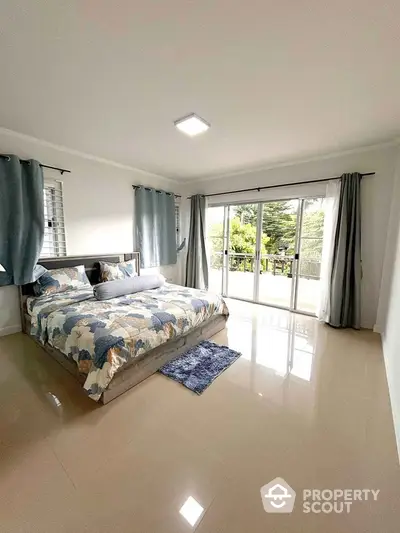 Spacious bedroom with large windows and balcony access, offering a serene view.