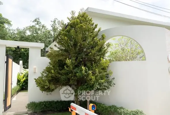 Modern minimalist home exterior with lush greenery and sleek architectural design.