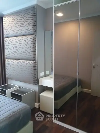 Modern bedroom with stylish decor and mirrored wardrobe in a cozy apartment.