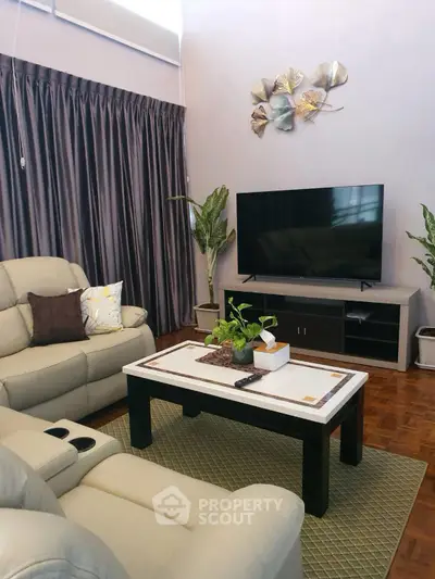 Cozy living room with modern decor, large TV, and comfortable seating, perfect for relaxation and entertainment.