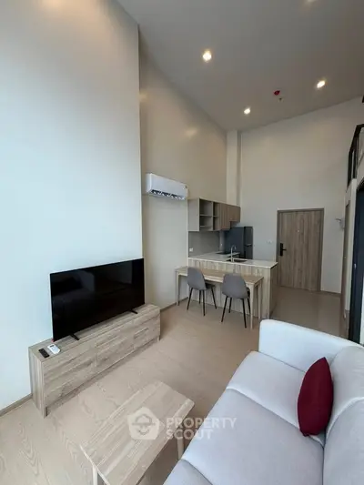 Modern living room with high ceiling, sleek furniture, and open kitchen layout in a stylish apartment.