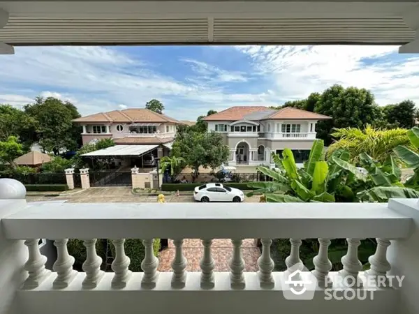 Charming view from a spacious balcony overlooking a serene neighborhood with lush greenery and elegant homes, perfect for relaxation.