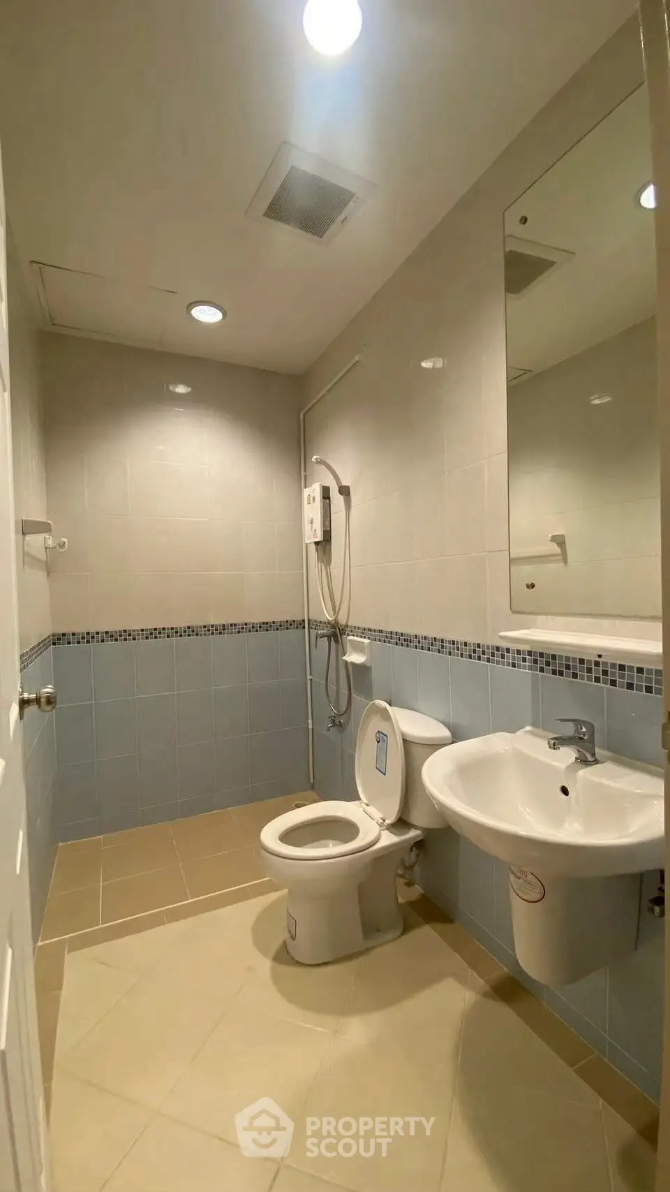 Modern bathroom with sleek fixtures and neutral tiles, featuring a shower and toilet.