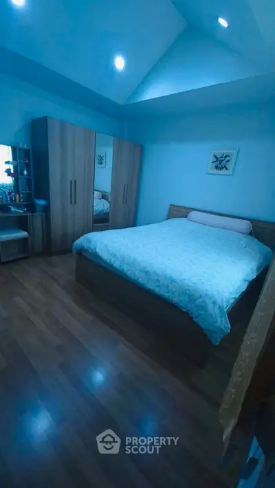 Cozy bedroom with wooden flooring and modern furniture, perfect for relaxation.