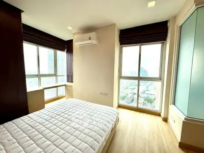 Spacious bedroom with large windows offering stunning city views in modern apartment.
