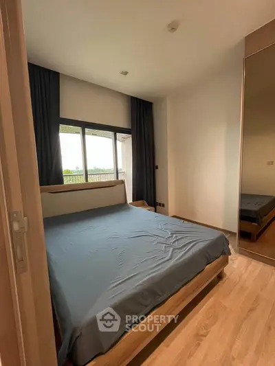 Spacious bedroom with large window and modern furnishings, offering a serene and comfortable living space.