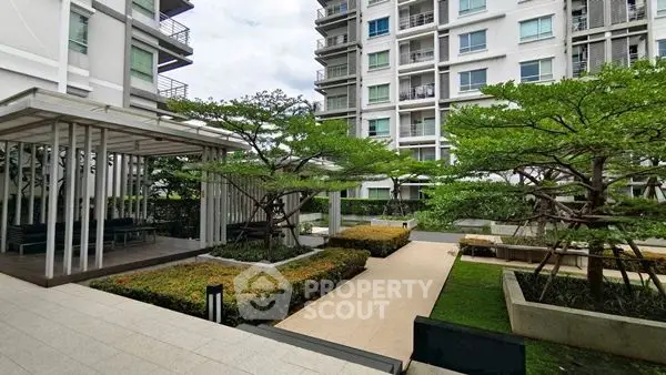 Modern apartment complex with landscaped garden and seating area.