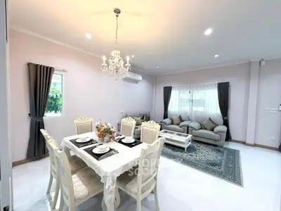 Elegant living and dining area with chandelier and cozy seating in modern home.