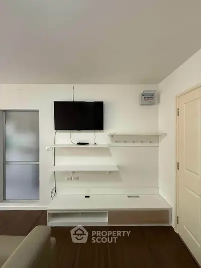 Modern living room with wall-mounted TV and sleek shelving in a stylish apartment.