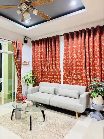 Charming living room with modern sofa, floral curtains, and glass coffee table.